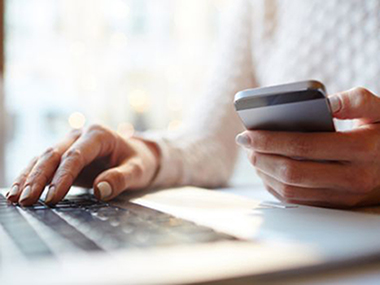 Female hands on laptop and cellphone